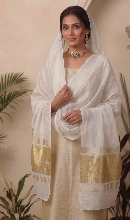 Woman wearing a white dupatta with gold patterns in an indoor setting